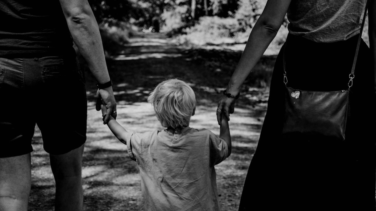 grayscale photo of woman in black dress holding child in black shirt